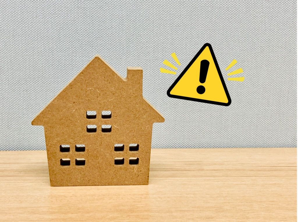 家の模型と警告サイン