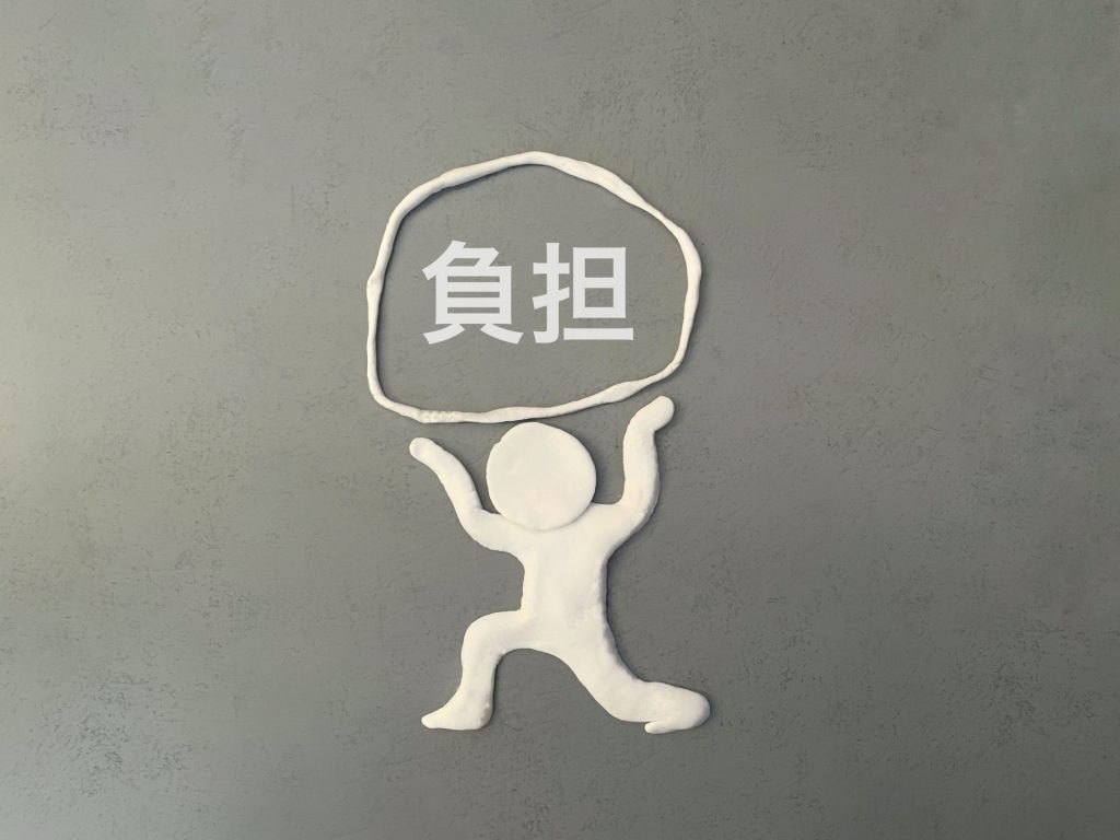 負担と書かれた重荷を支える白い人形